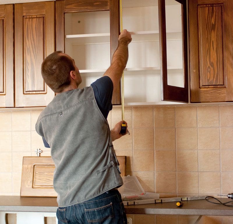 A Man installing cabinets in a kitchen remodel project