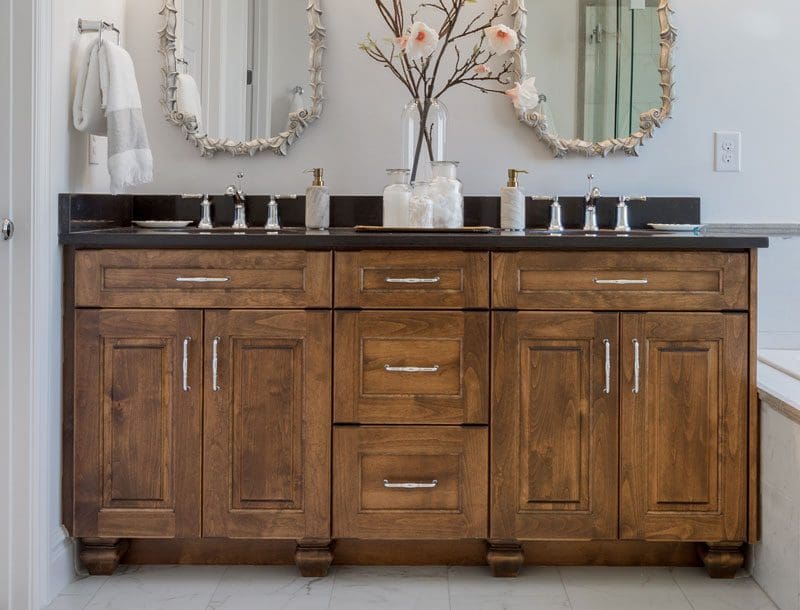 Rustic styled bathroom vanity with black countertop and distressed wood cabinets